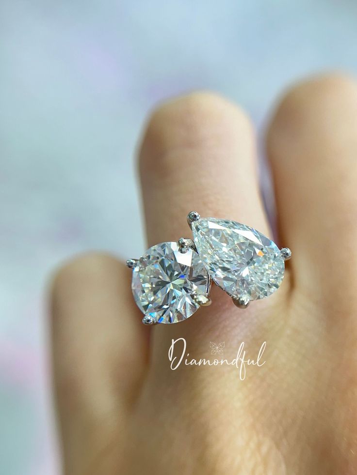 two pear shaped diamond engagement rings on someone's hand