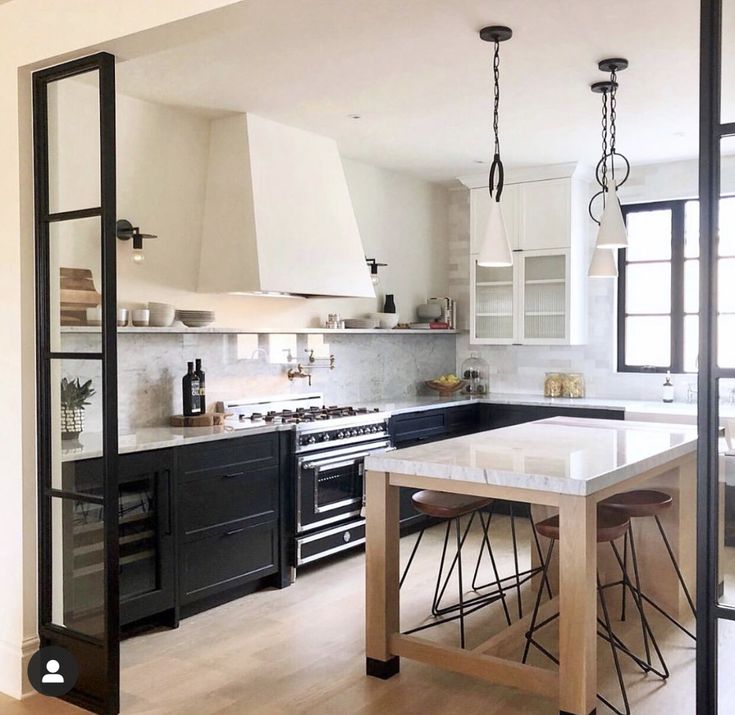 a kitchen with black cabinets and white counter tops, an island in the middle is surrounded by barstools