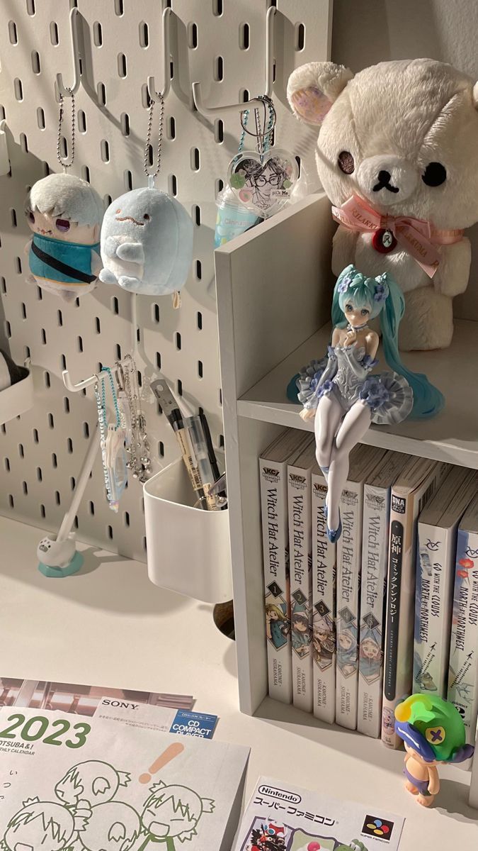 a teddy bear sitting on top of a book shelf next to other books and toys