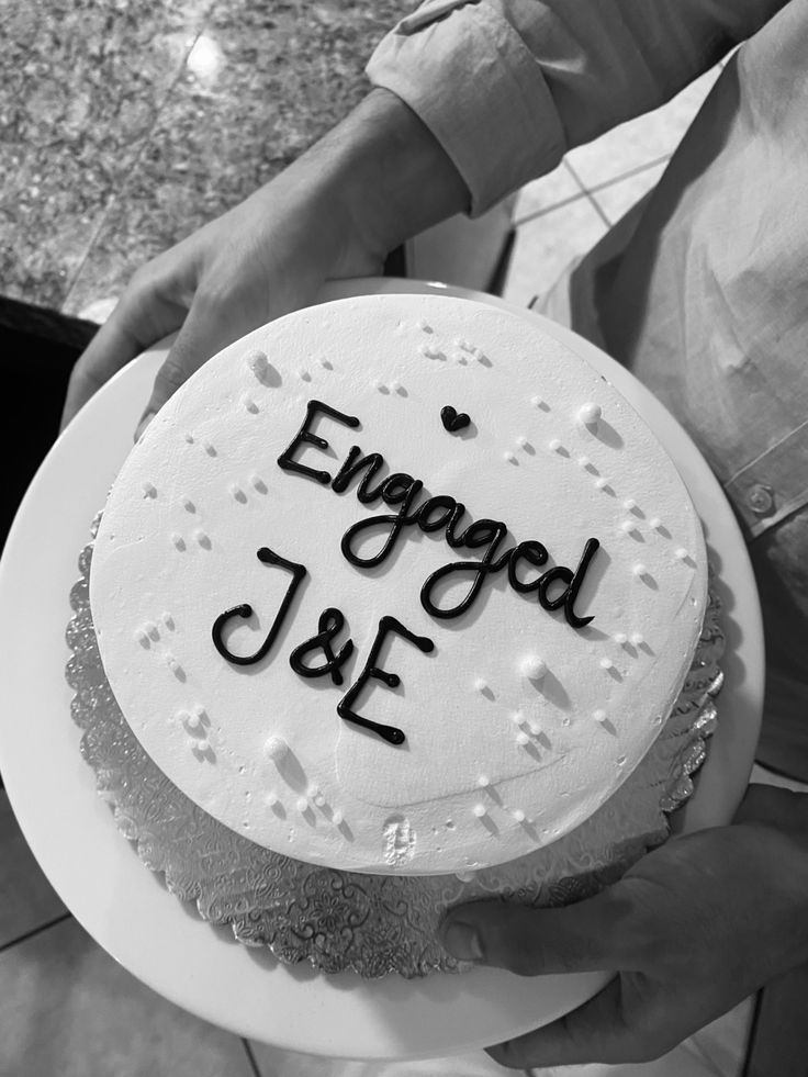 a cake with the words engaged j & f on it is being held by someone