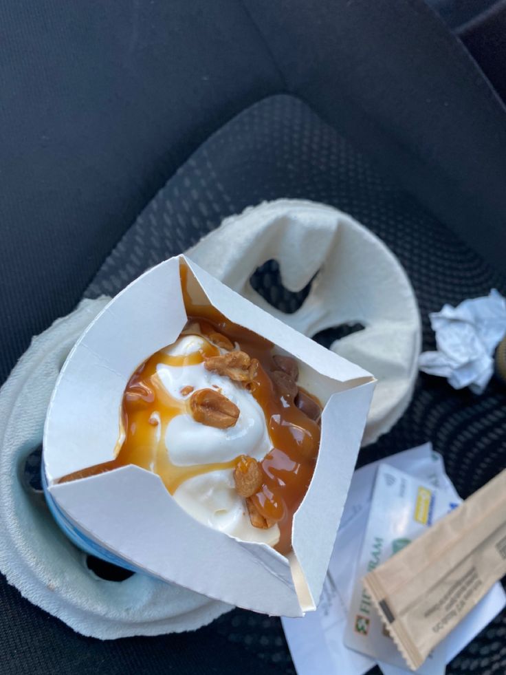 a cup filled with ice cream and caramel on top of a car seat cushion