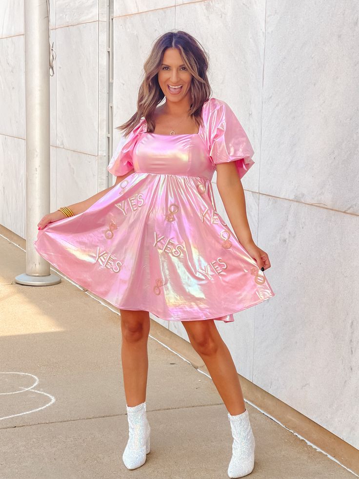 a woman in a pink dress and white shoes posing for the camera with her hand on her hip