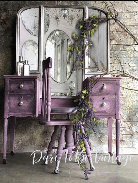 a purple vanity with mirror and flowers on it