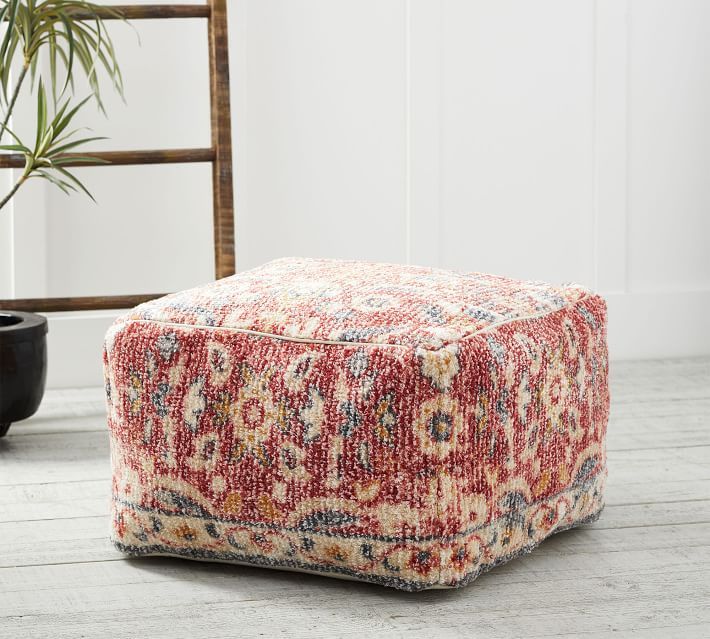 a red and white ottoman sitting on top of a wooden floor next to a potted plant