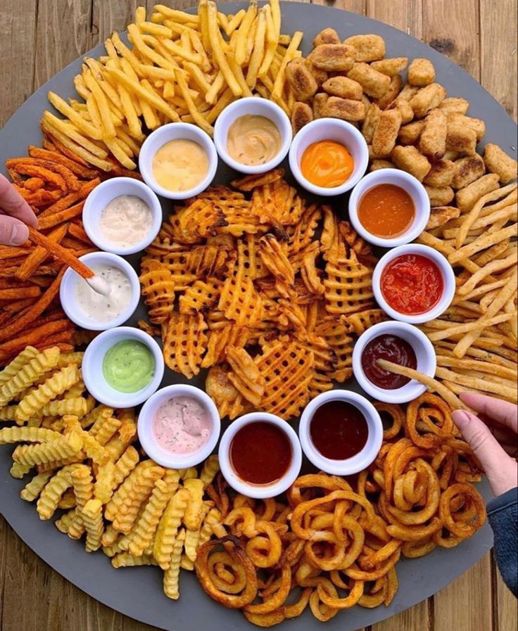 a platter filled with lots of different types of fries and dipping sauces on top of it