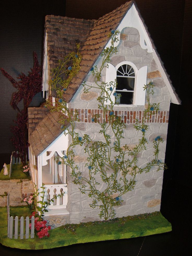 a doll house made out of clay with vines growing on the side of it and a small window