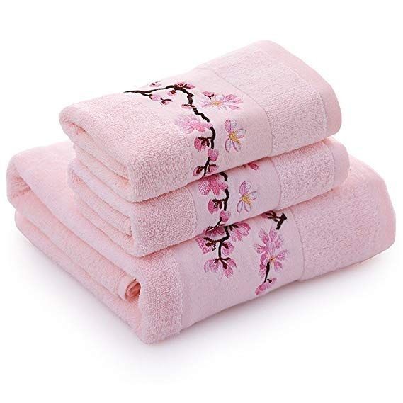 three pink towels stacked on top of each other in front of a white background with cherry blossoms