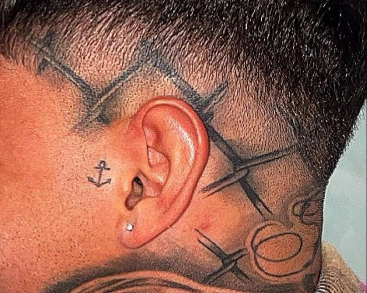 a man with tattoos on his head has scissors and an anchor behind the ear tattoo