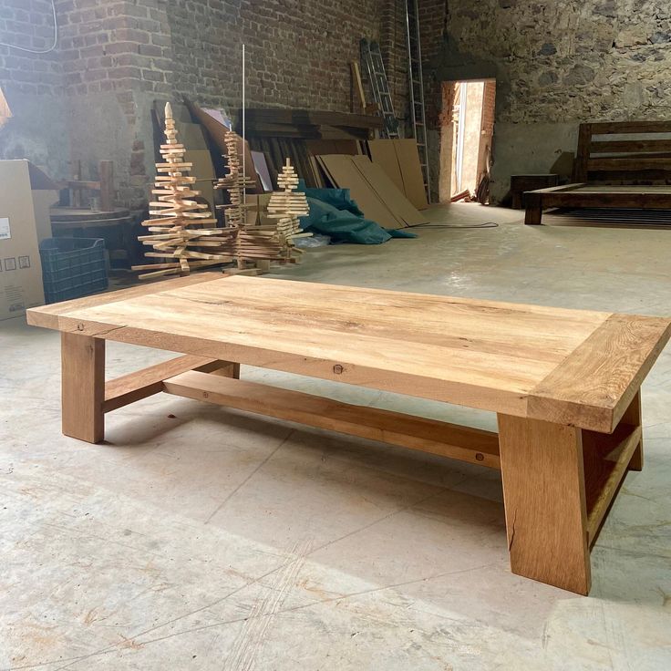 a wooden table sitting on top of a floor next to a pile of wood planks