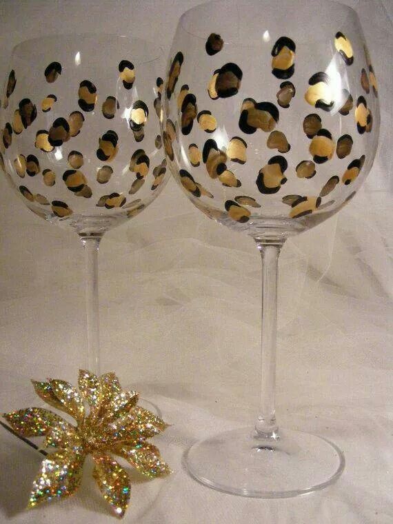 two wine glasses sitting next to each other on a white surface with gold foiled decorations