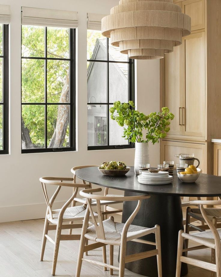 a dining room table and chairs with flowers in vases on the table next to it