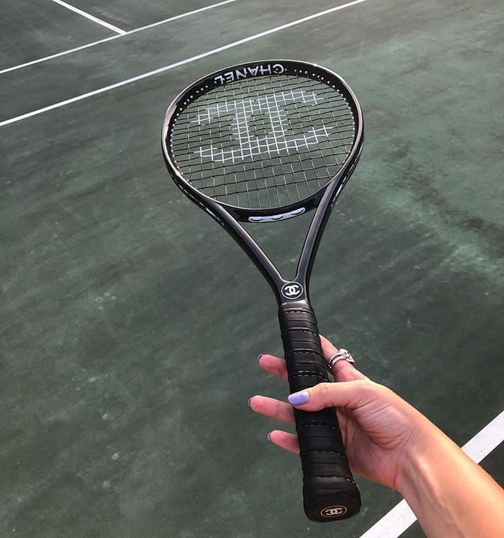 a person holding a tennis racquet on top of a hard surface tennis court