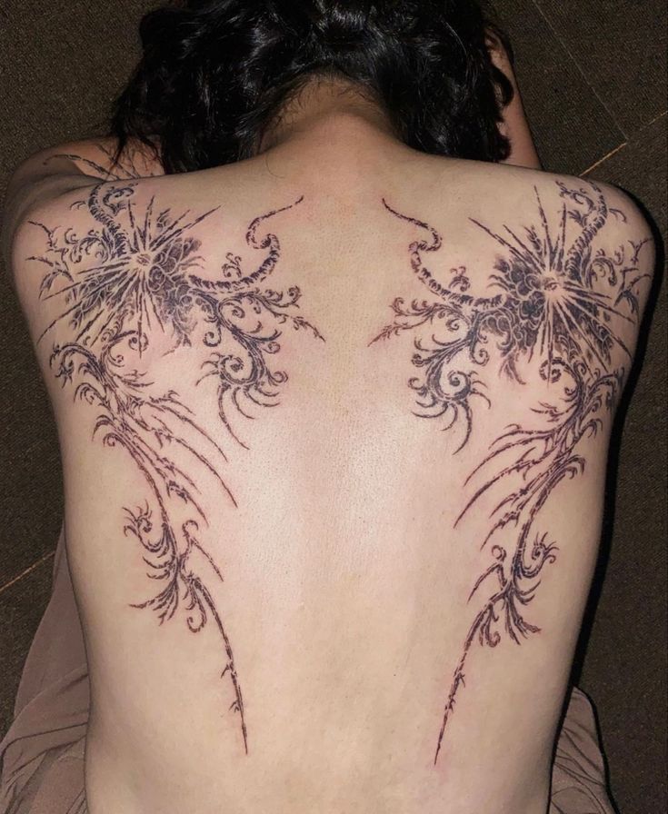 the back of a woman's body with tattoos on it