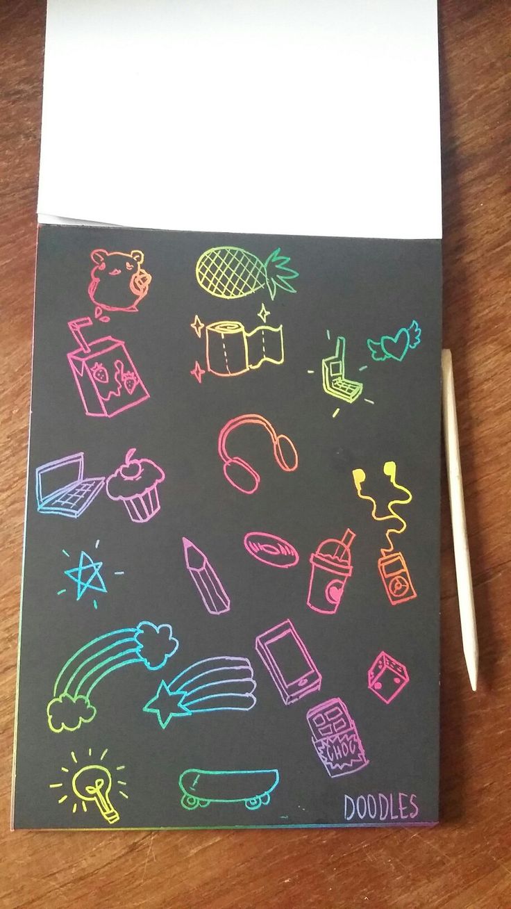 a notebook with doodles drawn on it sitting on top of a wooden table next to a pen