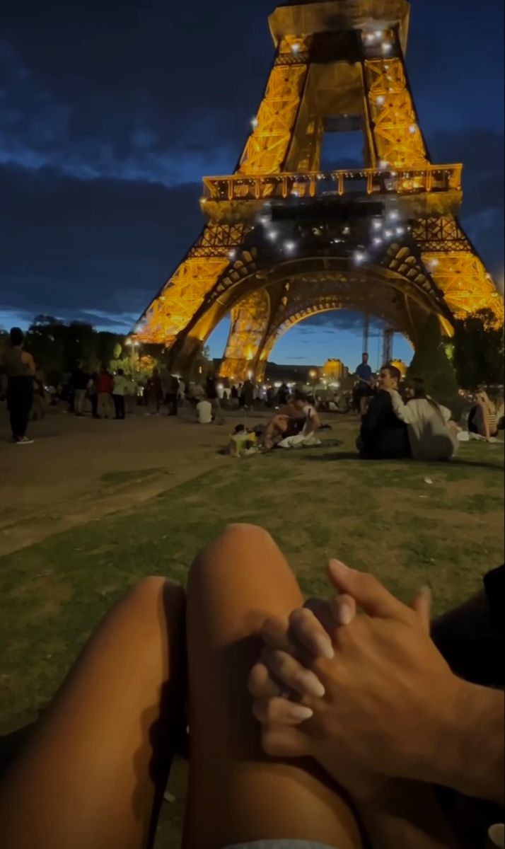 a person sitting in front of the eiffel tower at night