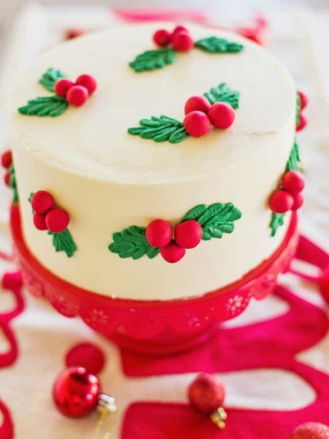 a white cake decorated with holly and red berries