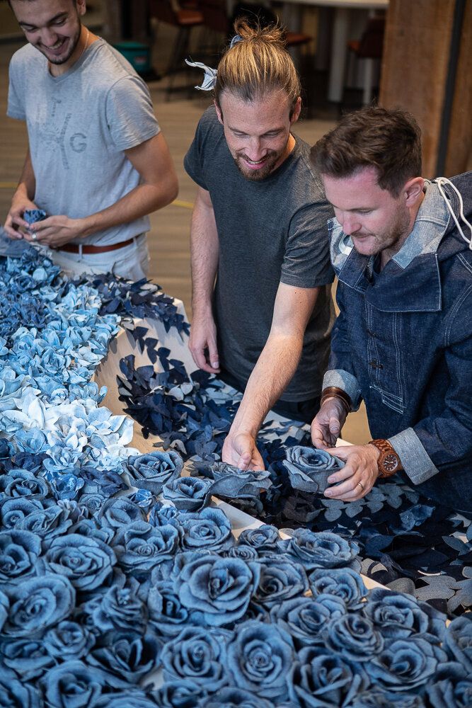 two men are working on something with blue flowers in the background and another man is looking at it