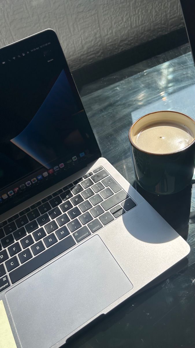 an open laptop computer sitting on top of a table next to a cup of coffee