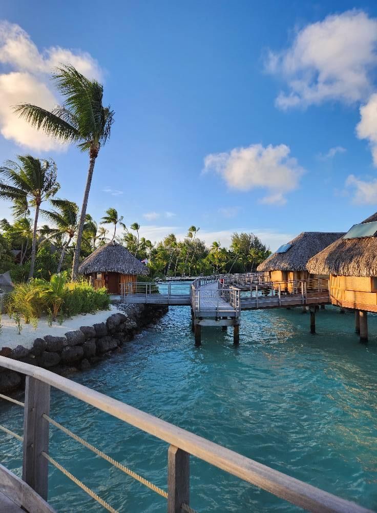 the water is clear and blue with some huts on it