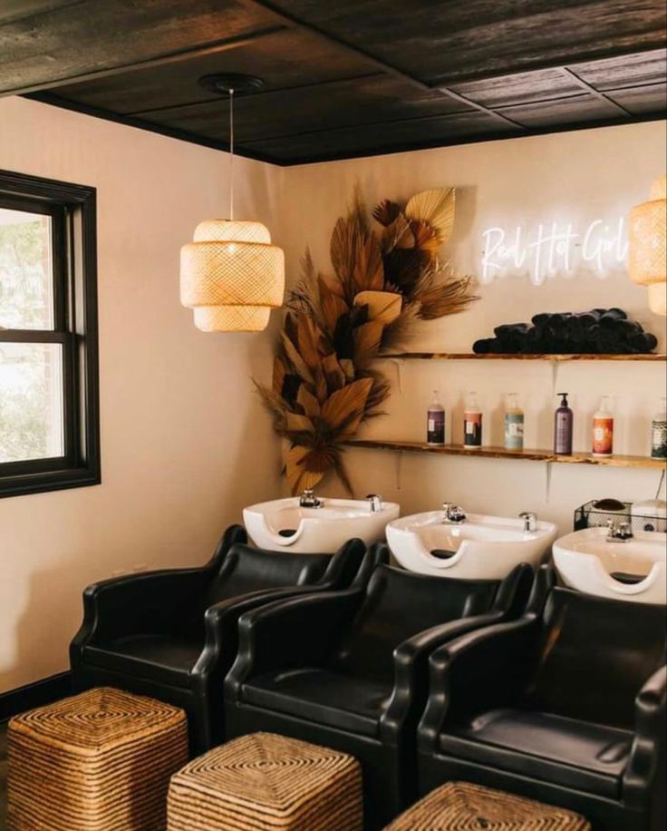 a row of black leather chairs sitting in front of a wall filled with bottles and soaps