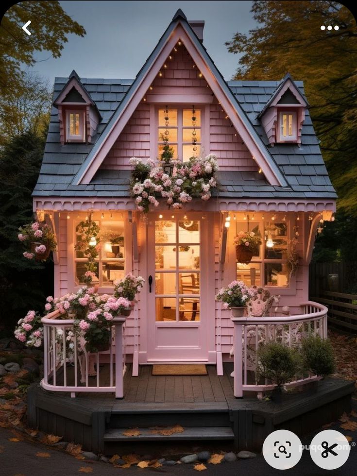 a small pink house with flowers on the porch