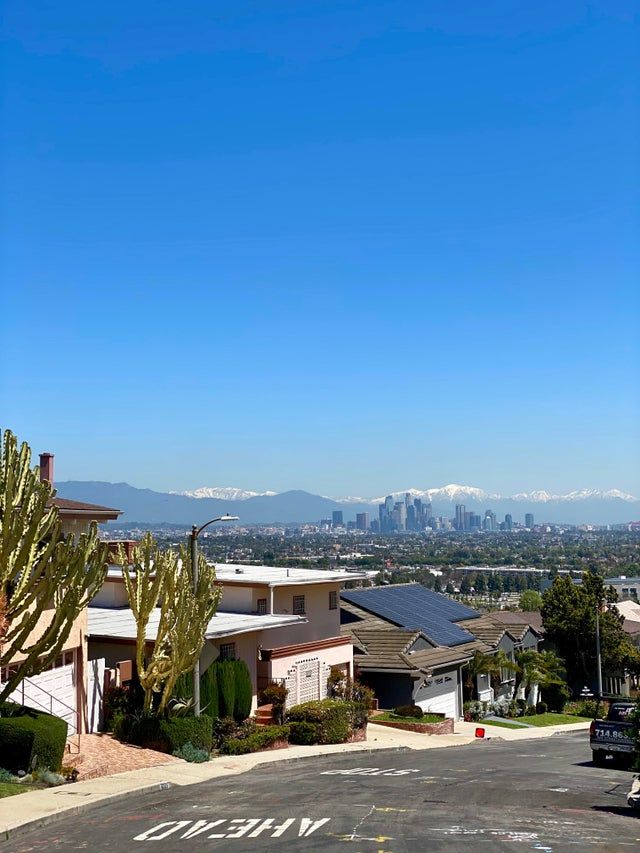 an empty parking lot in front of some houses with the city skyline in the background