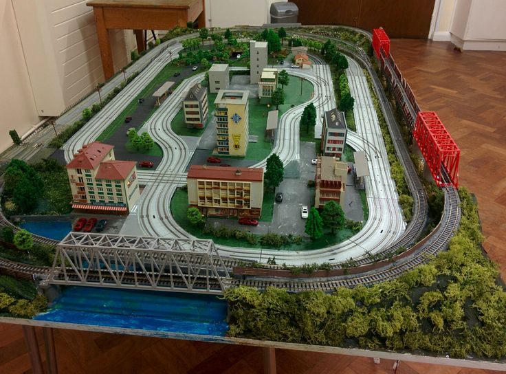 a model train set on display in a room with wooden floors and walls, along with a bridge