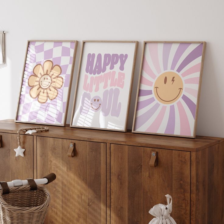 three framed pictures sitting on top of a wooden cabinet next to a wicker basket