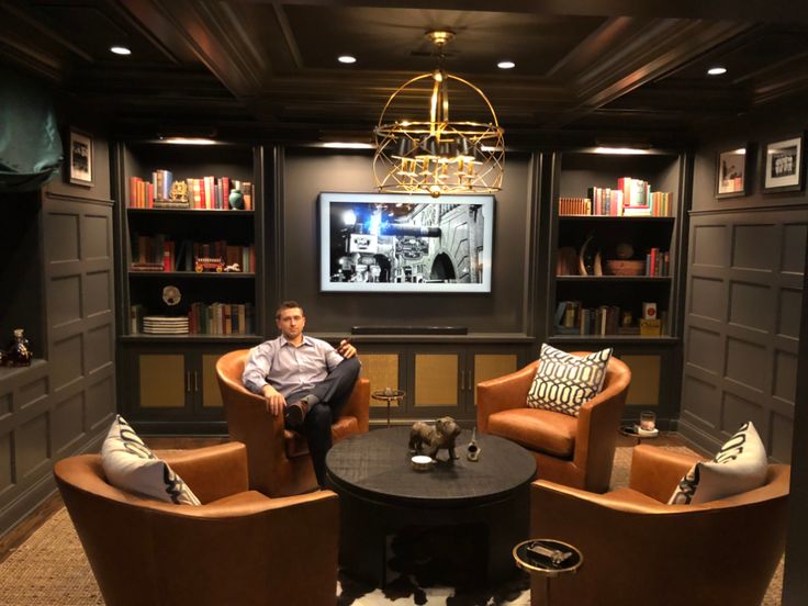 a man is sitting in the corner of a room with two chairs and a table