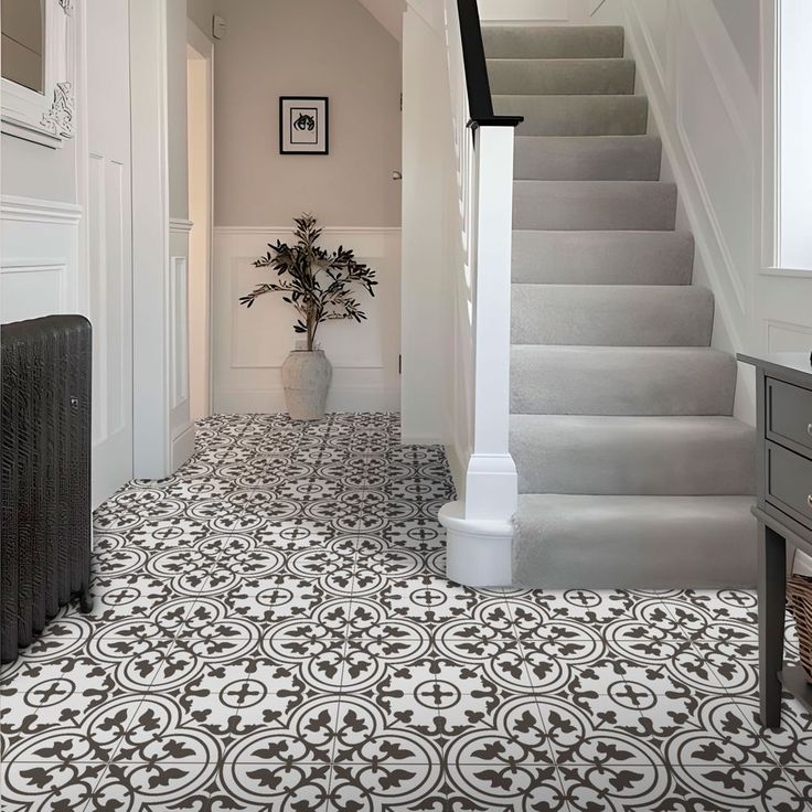 a white and black tiled floor next to a stair case with a potted plant