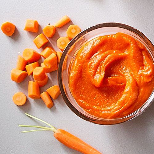 carrots and baby carrots are next to a small jar of orange colored sauce