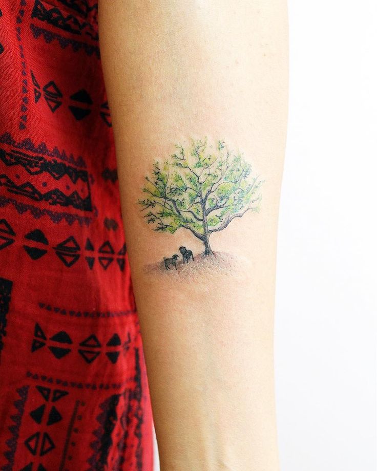 a woman's arm with a small tree and an animal tattoo on the left side of her arm