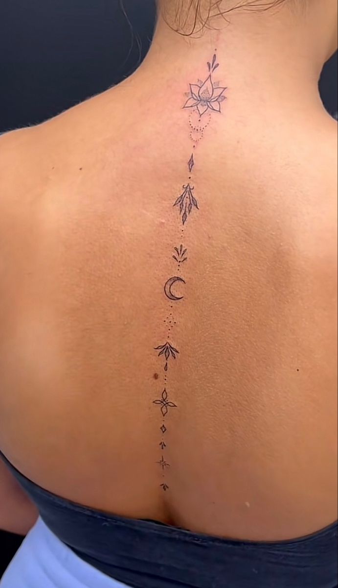 the back of a woman's neck with an arrow and moon tattoo on it