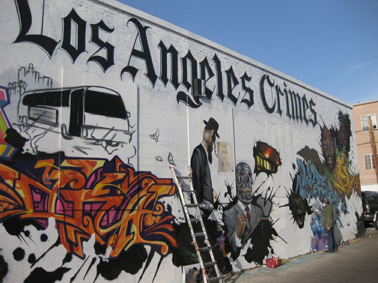 the side of a building with lots of graffiti on it's walls and ladders