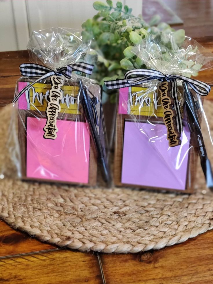 two small gift bags wrapped in cellophane and tied with ribbon on top of a woven placemat