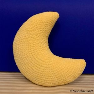 a knitted banana sitting on top of a wooden floor next to a blue wall