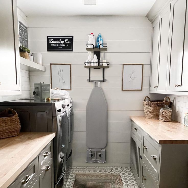 a laundry room with white walls and gray cabinets, an ironing board on the wall