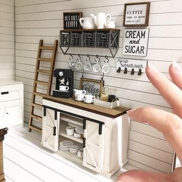 someone is holding their hand out to take a picture of a miniature kitchen and dining room