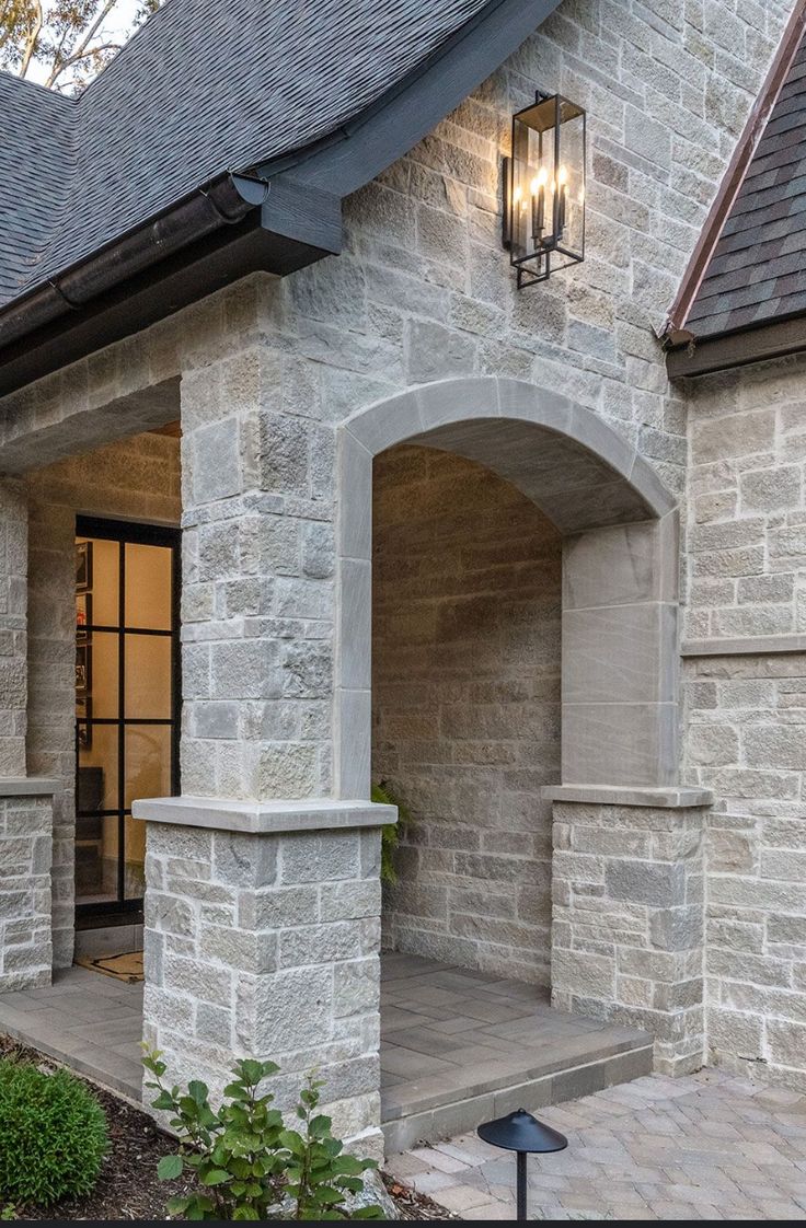 a stone house with two lights on the front door and side entrance to the home