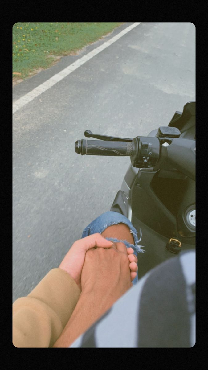 two people holding hands while riding a motorcycle