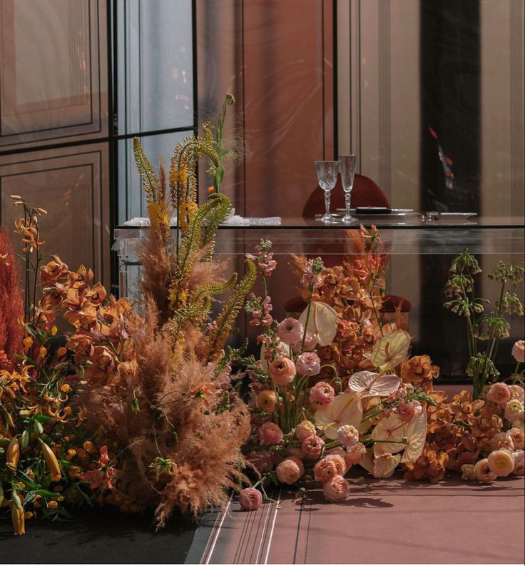 an arrangement of flowers and plants in front of a building