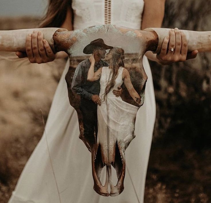 a woman in a white dress holding a steer with a cow skull on it's back