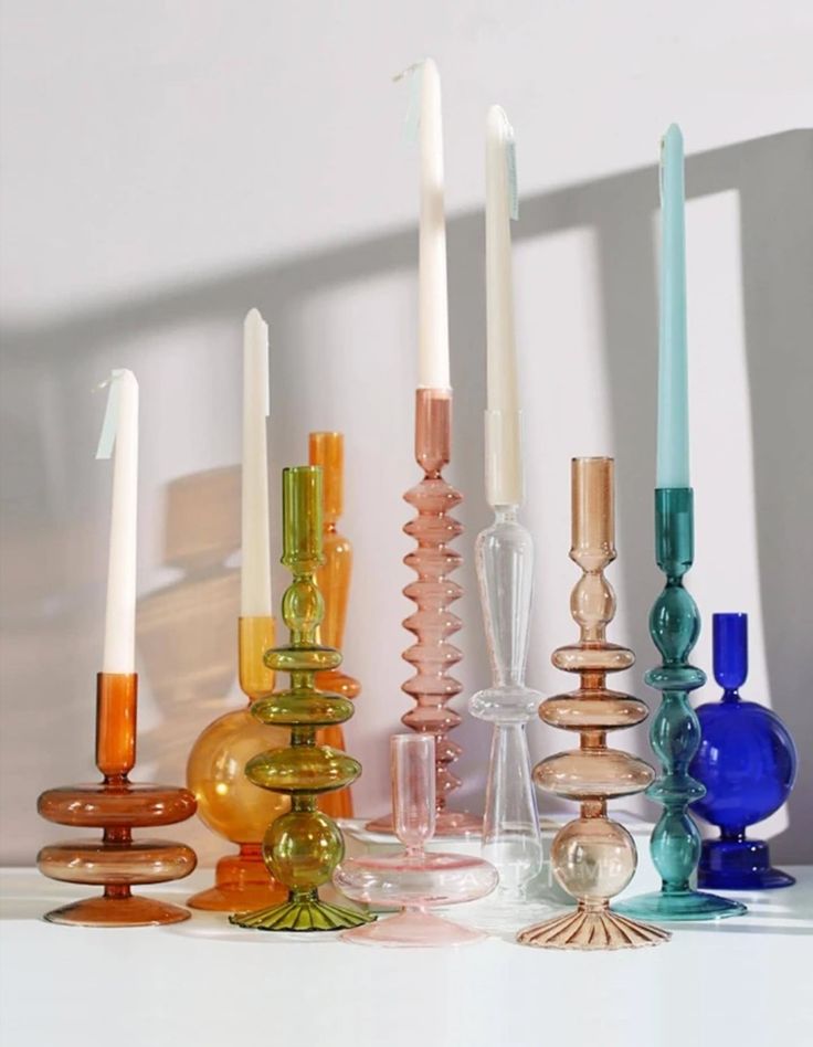 there are many different colored candles on the table