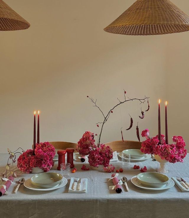 the table is set with pink flowers, candles and place settings for two people to sit at