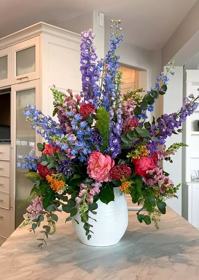 a white vase filled with lots of flowers on top of a table in a kitchen