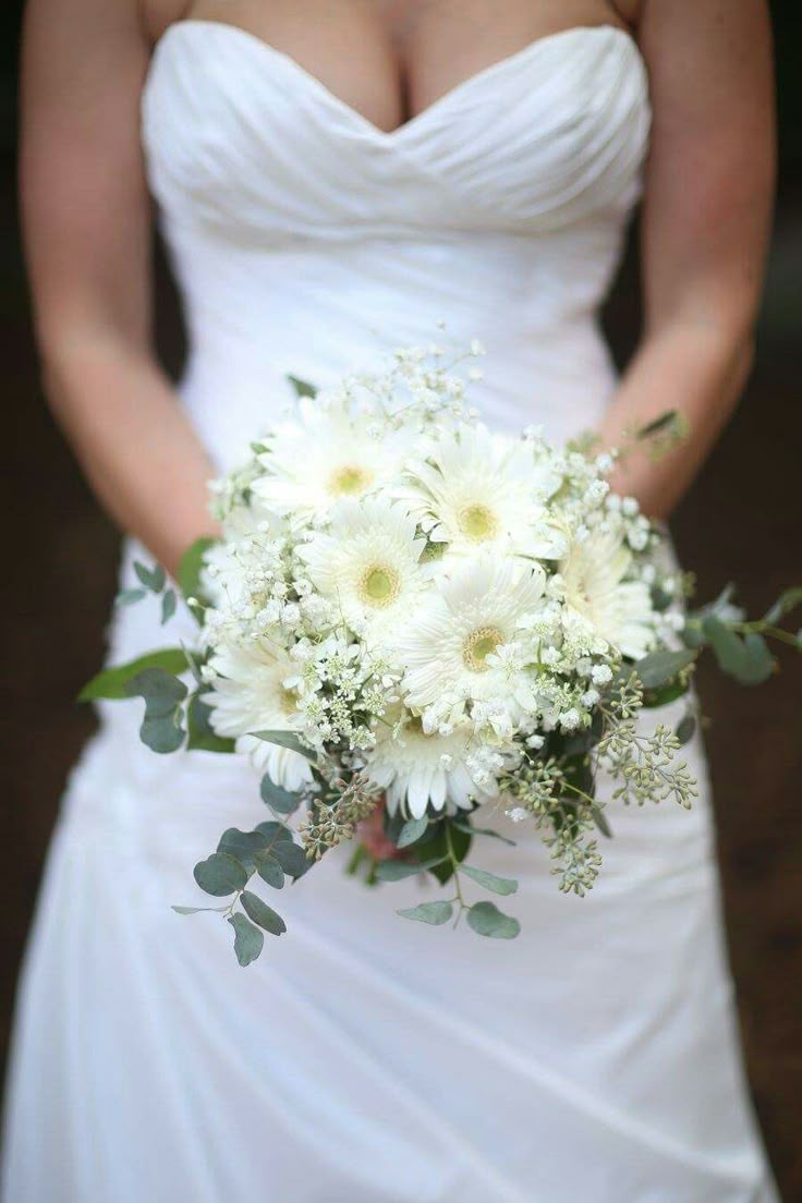 a bride holding a bouquet of white flowers