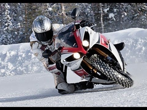 a man riding on the back of a motorcycle down a snow covered slope