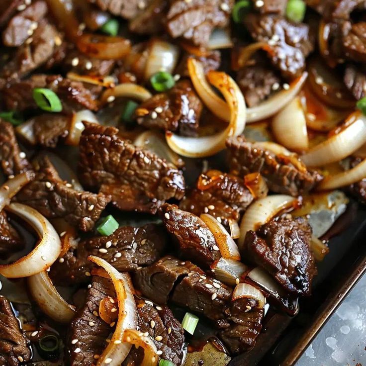 beef and onions are being cooked in a pan