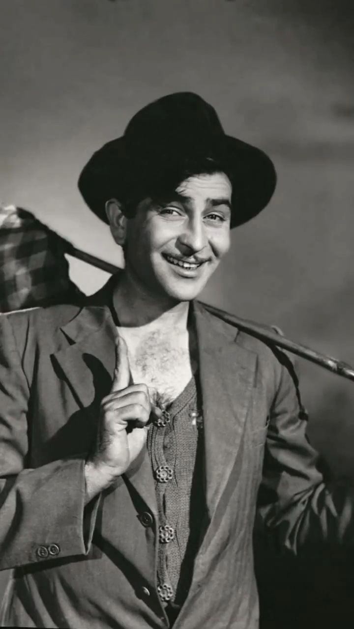 a man in a suit and hat holding an umbrella over his shoulder while smiling at the camera