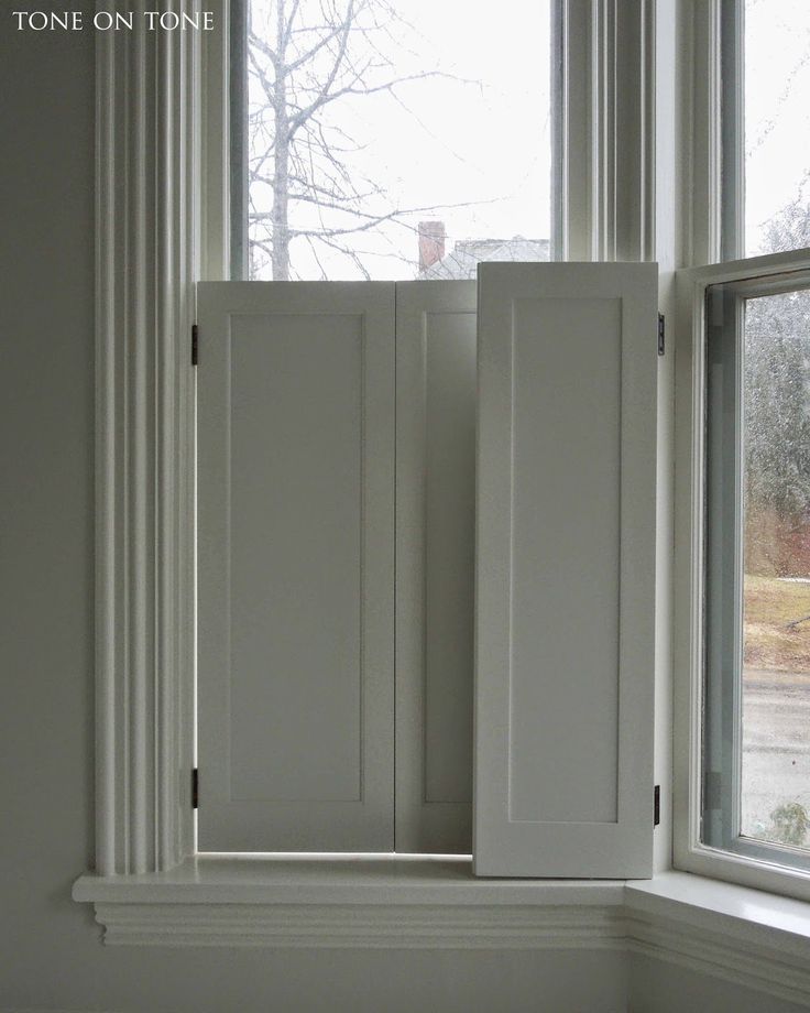 an empty window sill in front of a white painted wall with two doors open